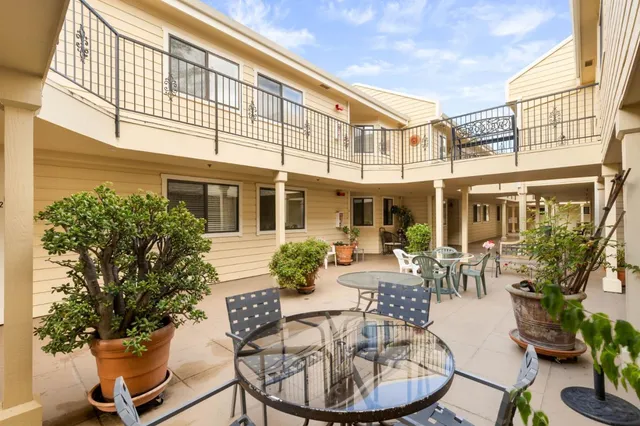 a view of a patio with a dining table and chairs and potted plants