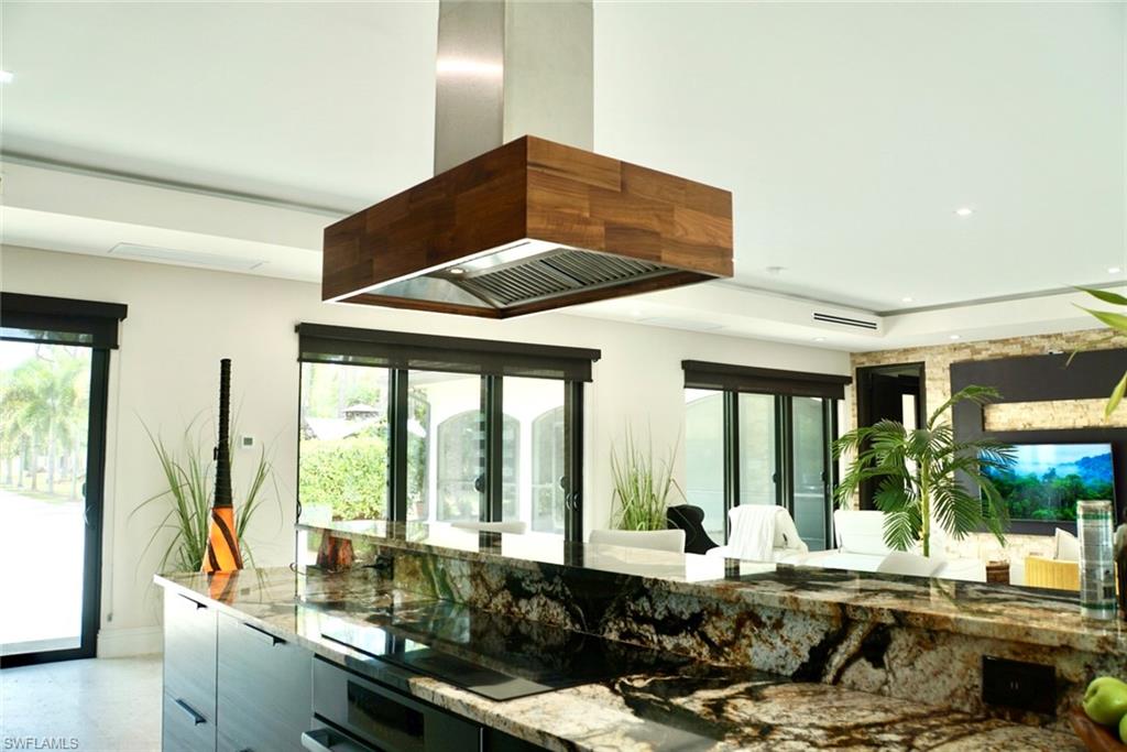 1391 Oakes Boulevard Naples, FL 34119 - Photo 22 of 43 Kitchen featuring island range hood, black electric stovetop, stone countertops, and oven