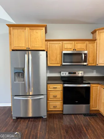 a view of kitchen with stainless steel appliances wooden floor and wooden cabinets