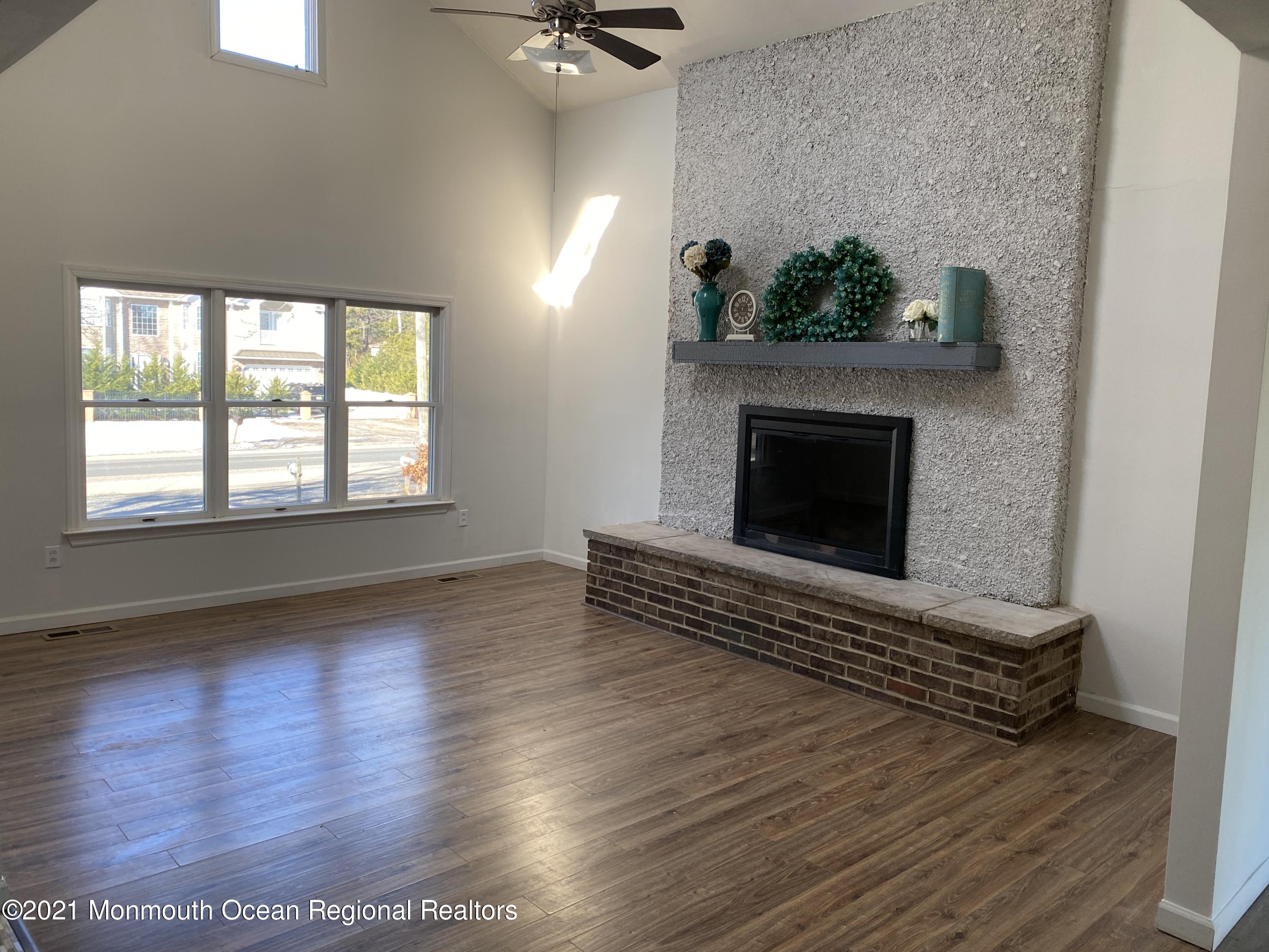 295 Western Boulevard Bayville, NJ 08721 - Photo 3 of 11 an empty room with wooden floor a fireplace and windows