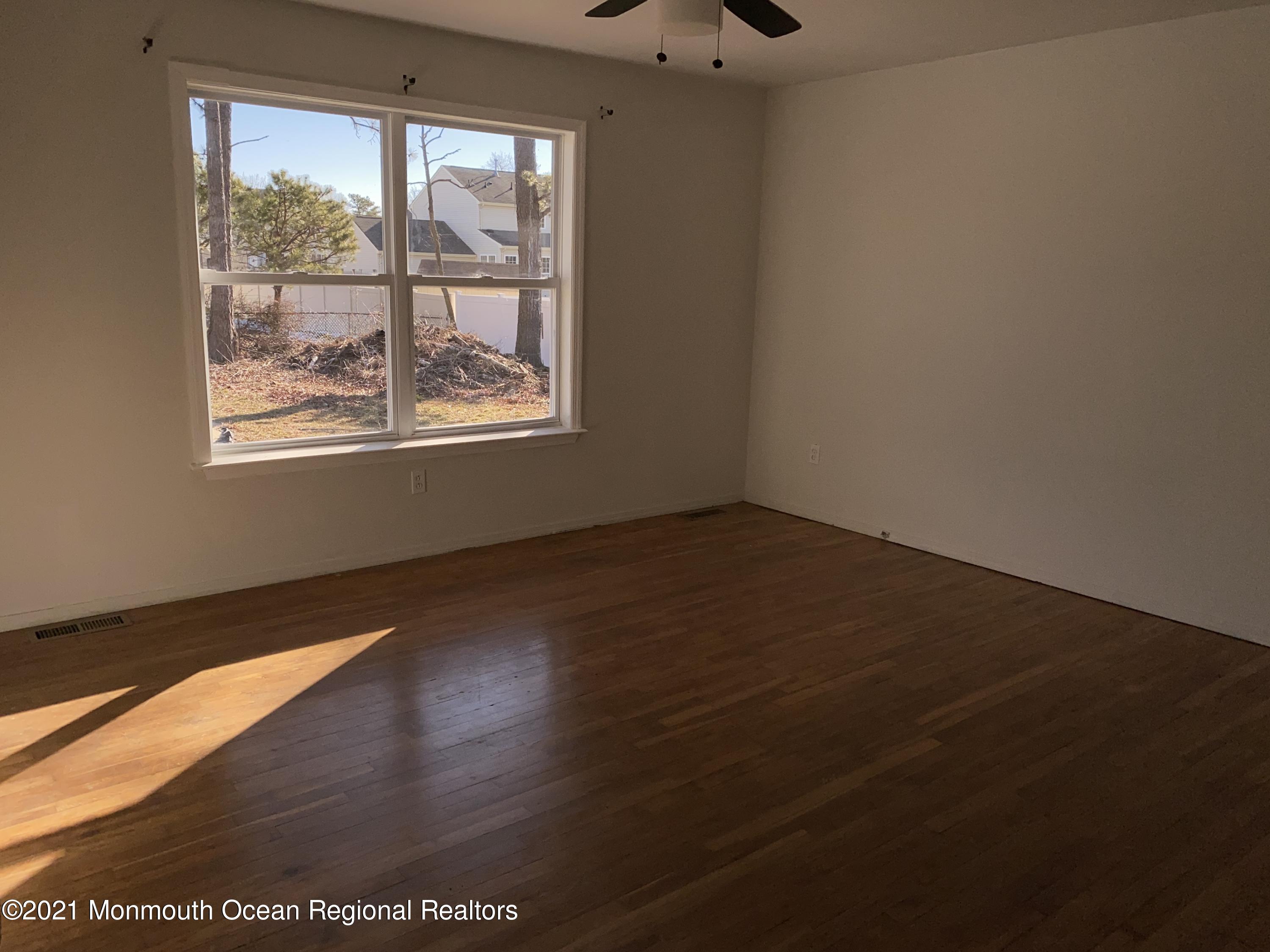 295 Western Boulevard Bayville, NJ 08721 - Photo 8 of 11 an empty room with wooden floor and windows
