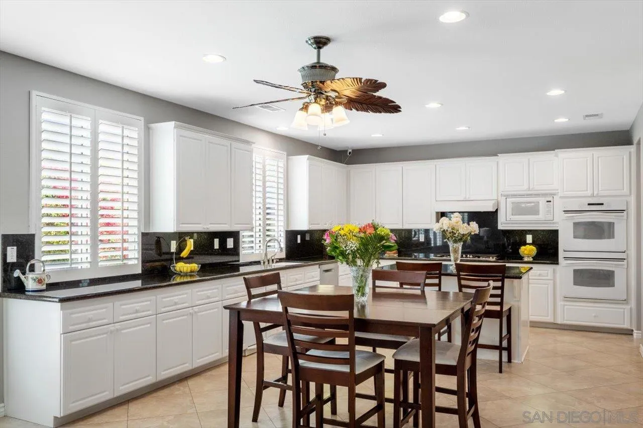 565 Hidden Trails Road Escondido, CA 92027 - Photo 19 of 52 a kitchen with stainless steel appliances kitchen island granite countertop a table chairs sink and cabinets