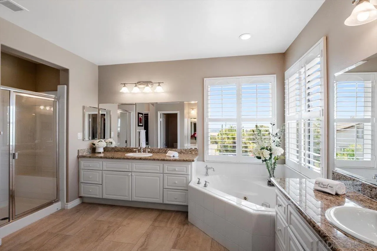 565 Hidden Trails Road Escondido, CA 92027 - Photo 30 of 52 a bathroom with a granite countertop sink mirror and a bathtub