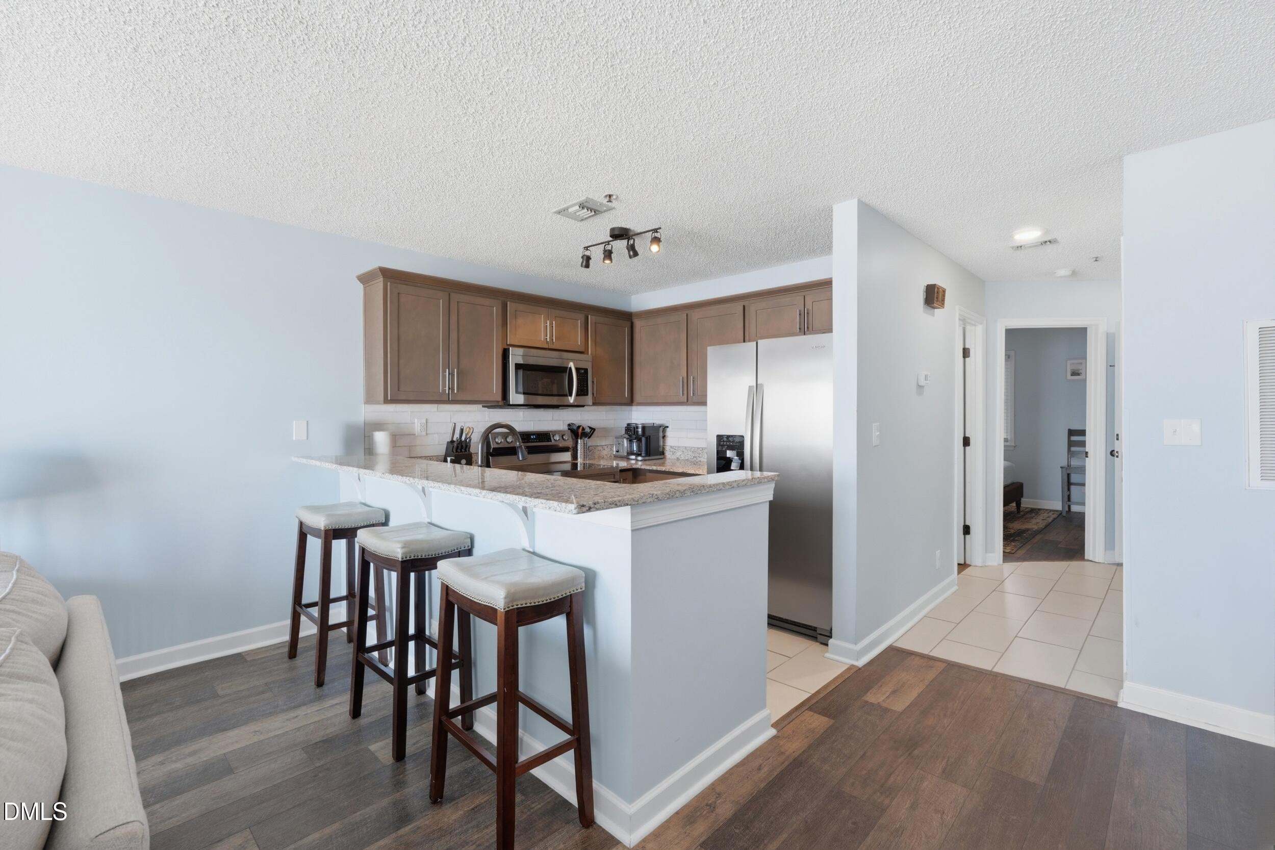 790 New River Inlet Road, Unit 114A North Topsail Beach, NC 28460 - Photo 18 of 46 a kitchen with stainless steel appliances granite countertop a table chairs refrigerator and a sink