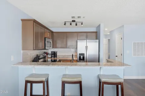 a kitchen with stainless steel appliances granite countertop a table chairs refrigerator and a sink