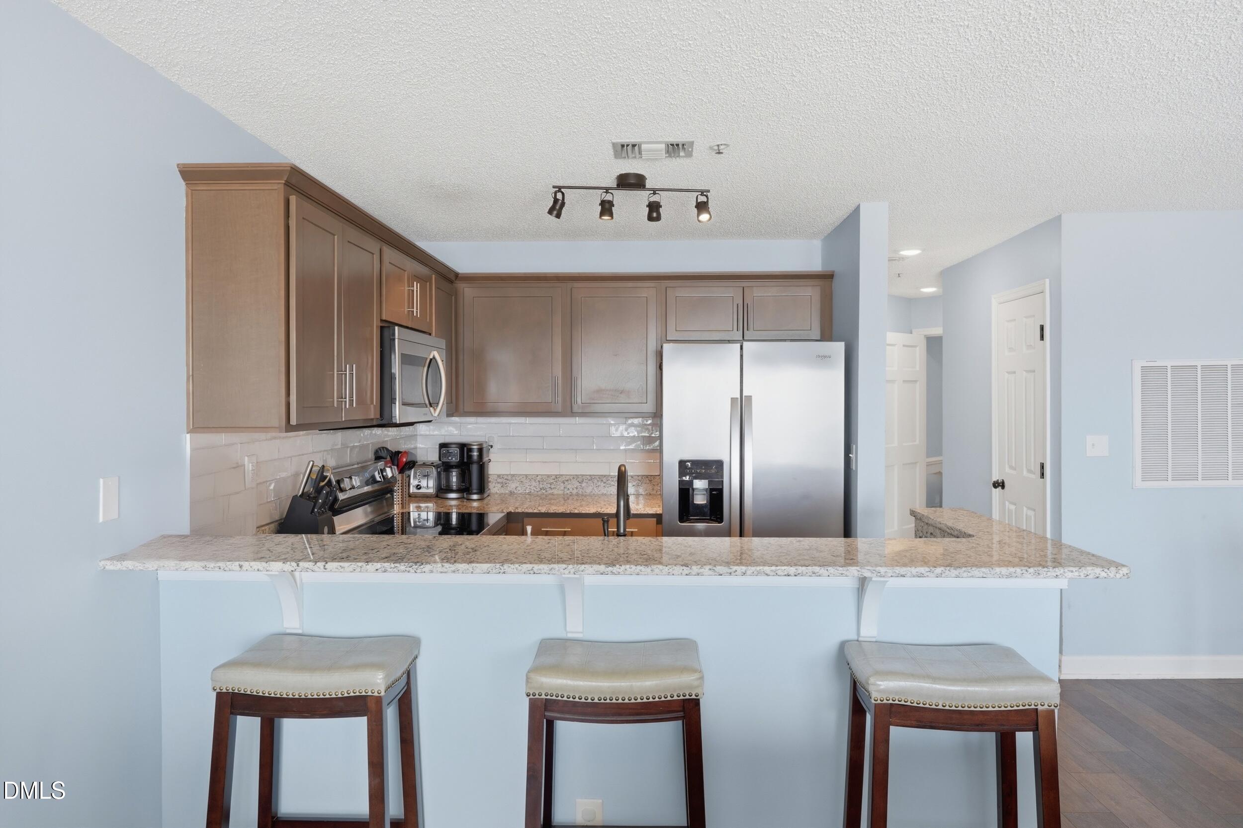790 New River Inlet Road, Unit 114A North Topsail Beach, NC 28460 - Photo 19 of 46 a kitchen with refrigerator a sink and chairs