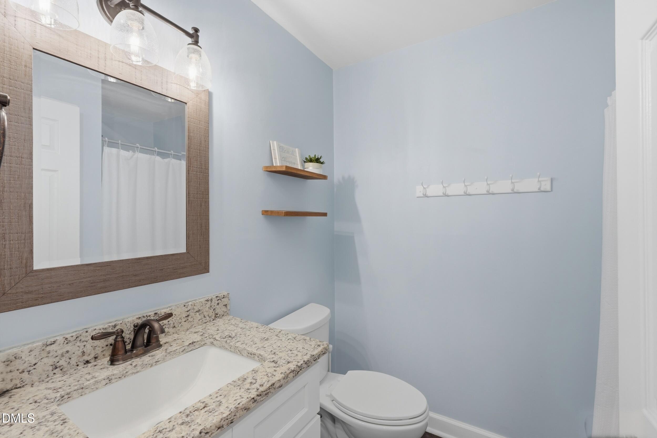 790 New River Inlet Road, Unit 114A North Topsail Beach, NC 28460 - Photo 9 of 46 a bathroom with a granite countertop sink a toilet and mirror