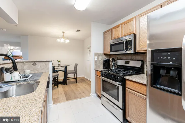 a kitchen with stainless steel appliances kitchen island granite countertop a sink and stove top oven with wooden floor
