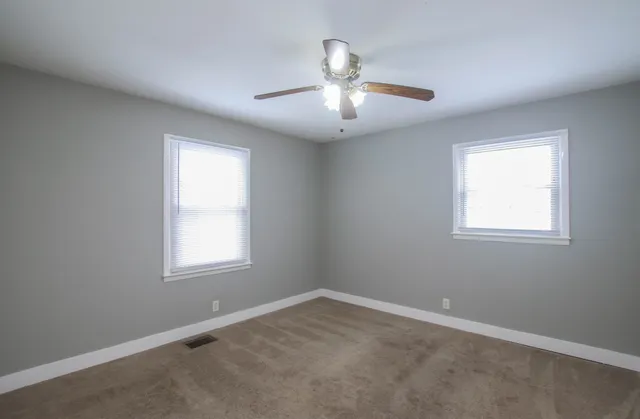 an empty room with a window and ceiling fan