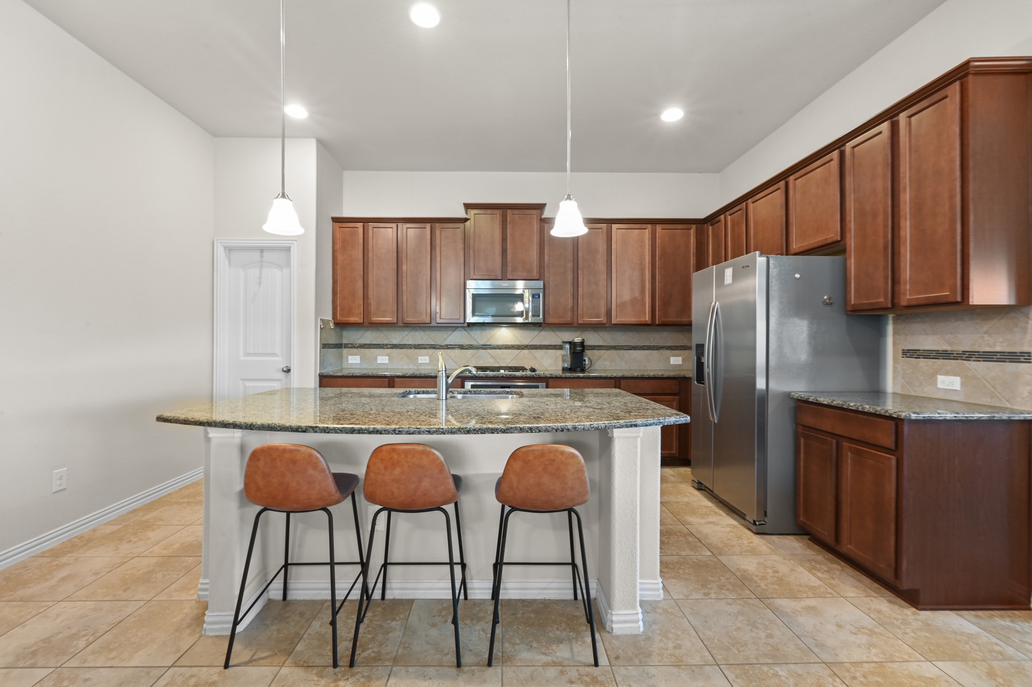 877 Hot Spring Valley Buda, TX 78610 - Photo 8 of 36 a kitchen with granite countertop a refrigerator and wooden cabinets
