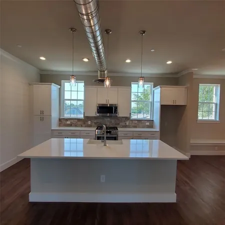 a large kitchen with kitchen island a large counter space a sink a window and appliances