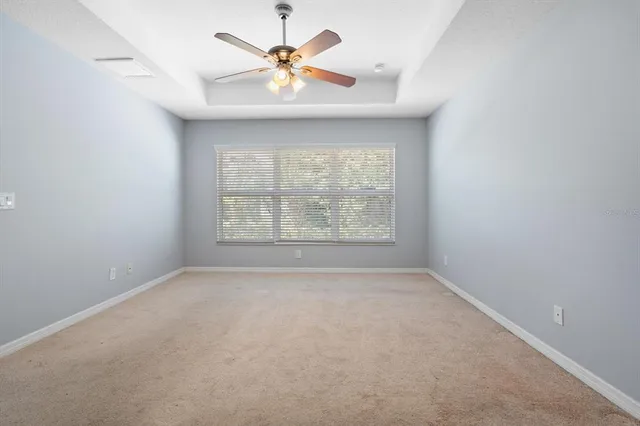 an empty room with a window and a ceiling fan
