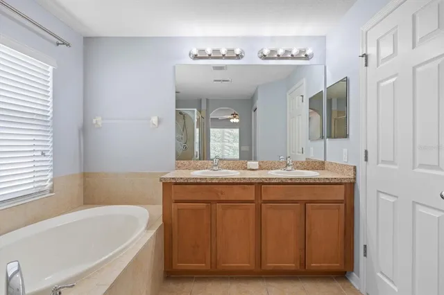 a bathroom with a granite countertop sink mirror and bathtub