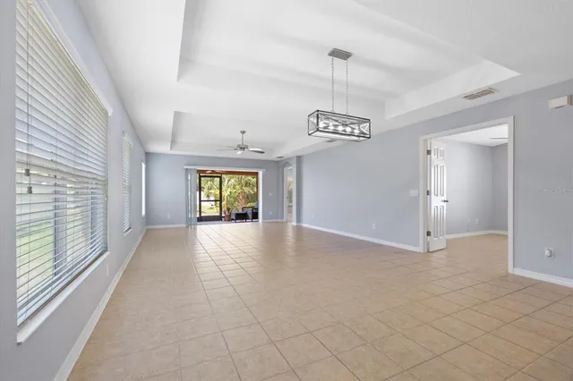 a view of an empty room with window and chandelier fan