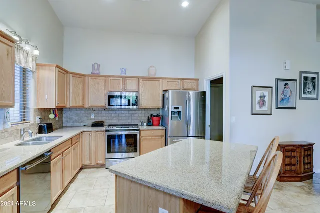 a kitchen with stainless steel appliances granite countertop a stove top oven a sink a dining table and chairs