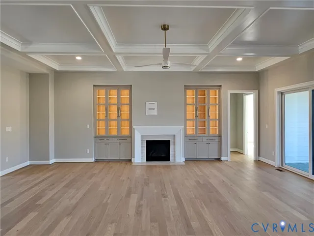 an empty room with wooden floor fireplace and windows