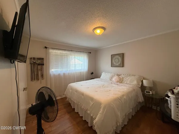 a bedroom with a bed and a flat tv screen on the dresser