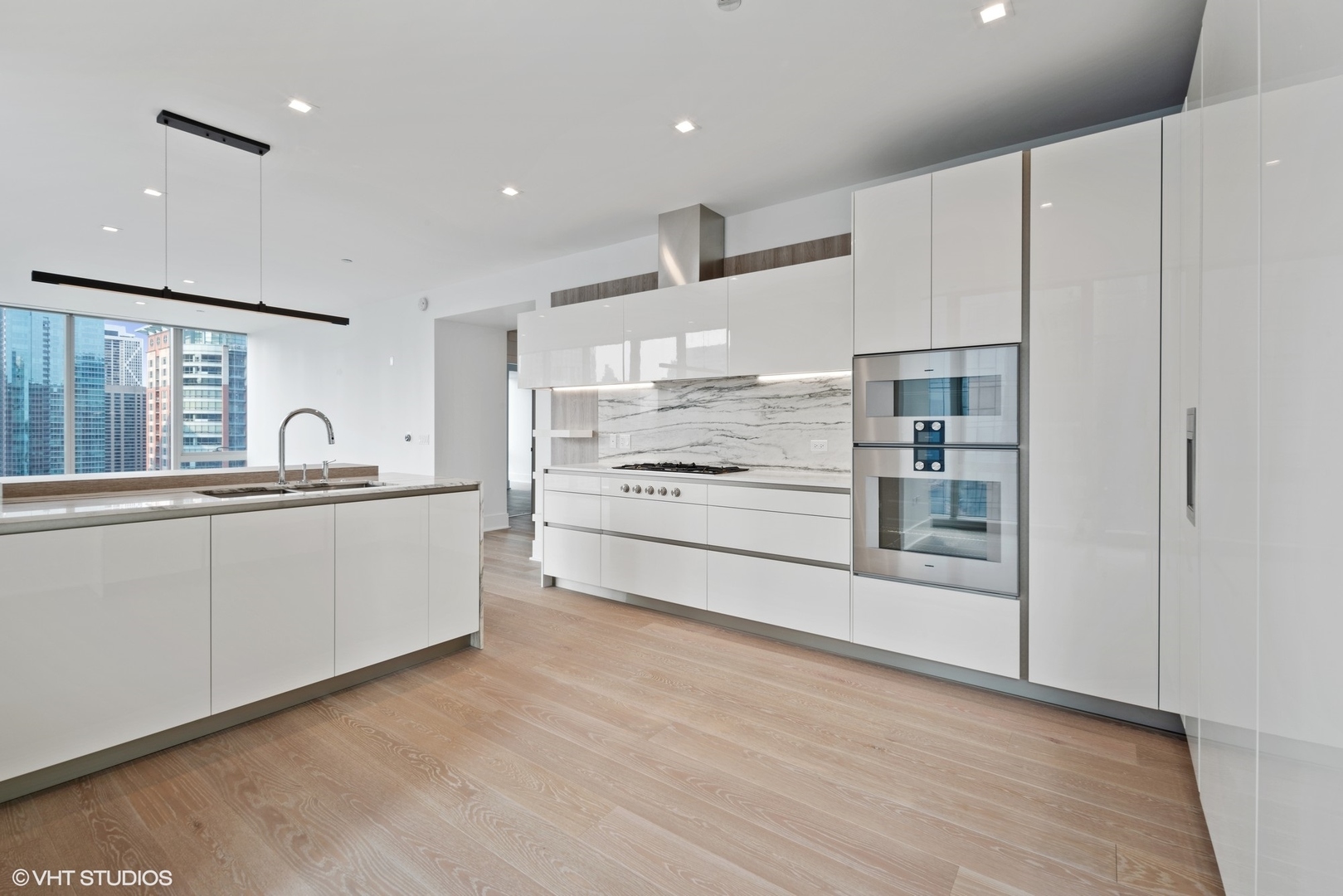 363 East Wacker Drive, Unit 1802 Chicago, IL 60601 - Photo 4 of 15 a large white kitchen with kitchen island a sink stainless steel appliances and cabinets
