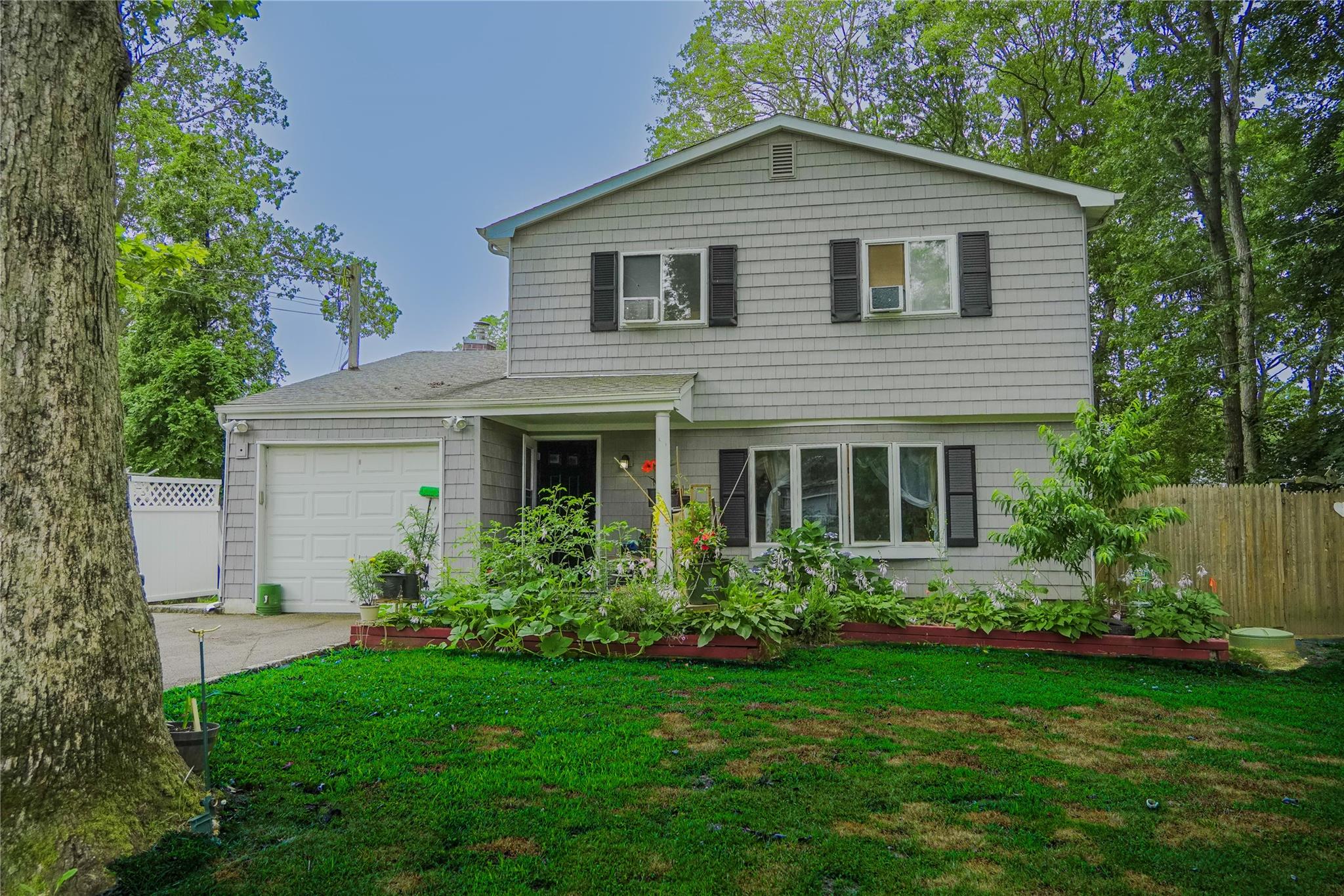 172 Hampton Avenue Mastic, NY 11950 - Photo 1 of 1 View of front facade with a garage and concrete driveway