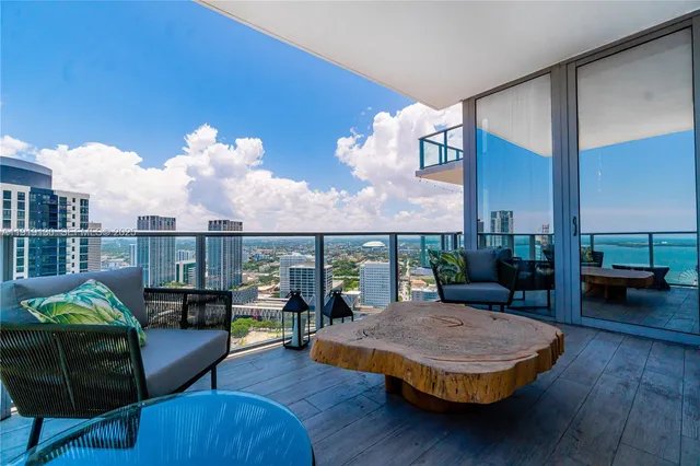 a living room with couches and kitchen view with wooden floor