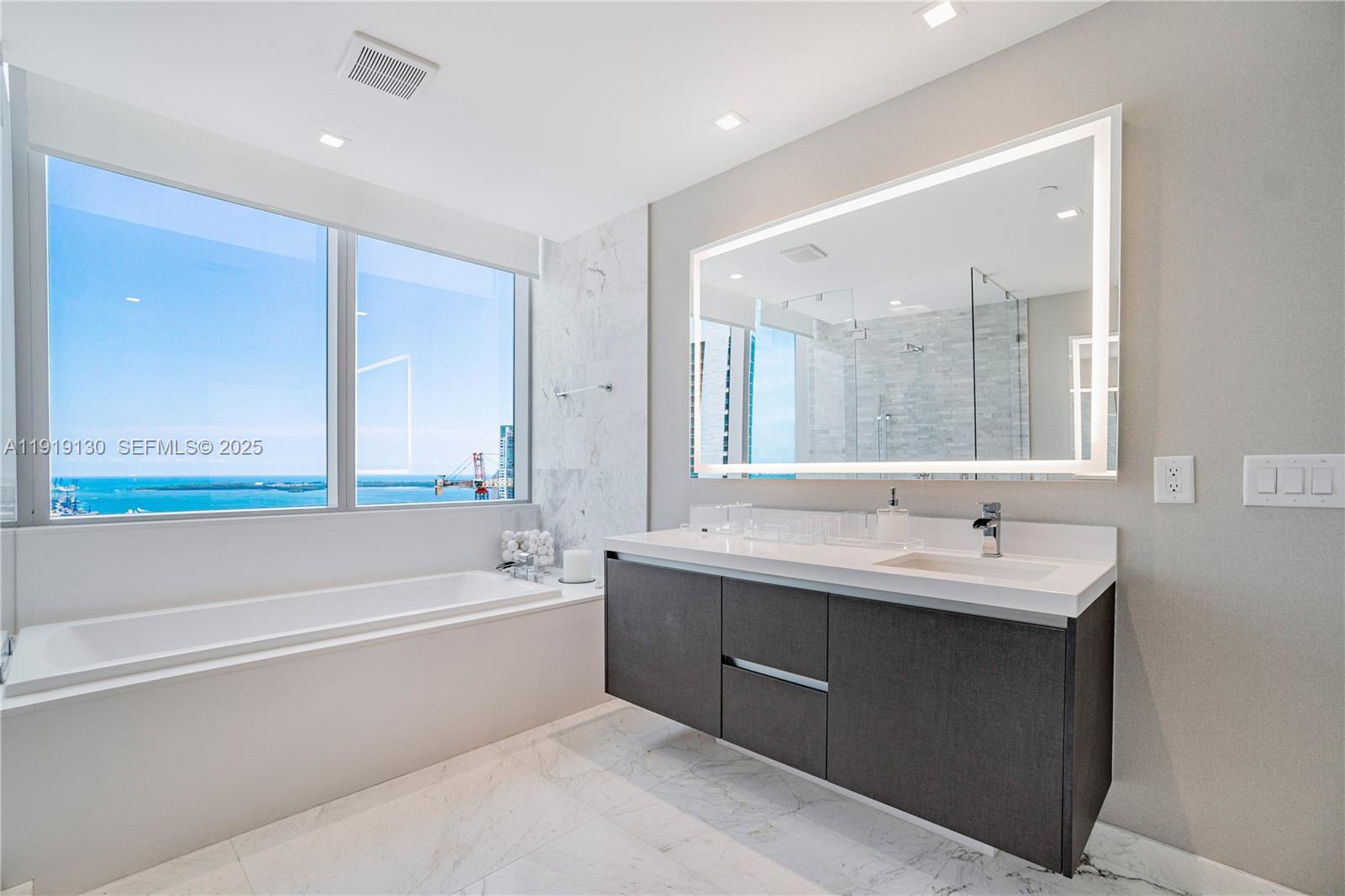 851 Northeast 1st Avenue, Unit 3511 Miami, FL 33132 - Photo 18 of 53 a bathroom with a bathtub a double vanity sink and mirror