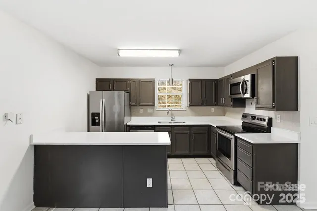 a kitchen with stainless steel appliances a sink a stove a microwave a sink a refrigerator and cabinets