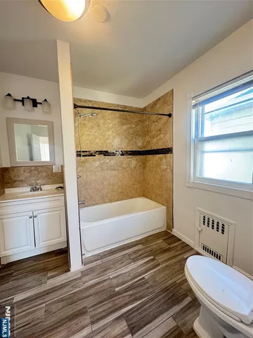 a bathroom with a granite countertop sink toilet a mirror and bathtub