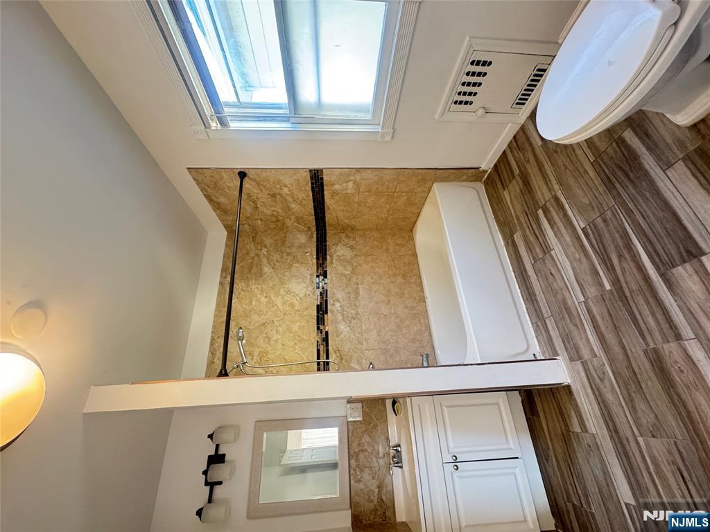 323 Devon Street, Unit 2 Kearny, NJ 07032 - Photo 7 of 8 a bathroom with a granite countertop sink toilet a mirror and bathtub