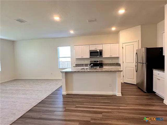 a kitchen with kitchen island sink stove and refrigerator