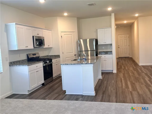 a large kitchen with stainless steel appliances granite countertop a stove a sink dishwasher and a refrigerator