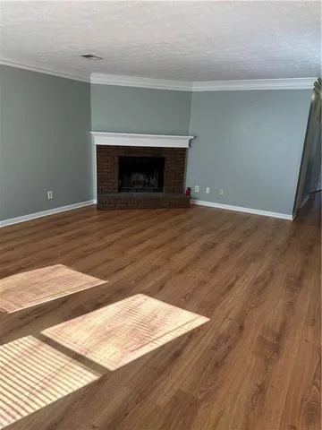 a view of an empty room with wooden floor and a fireplace
