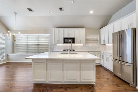 a kitchen with kitchen island granite countertop a sink appliances and cabinets