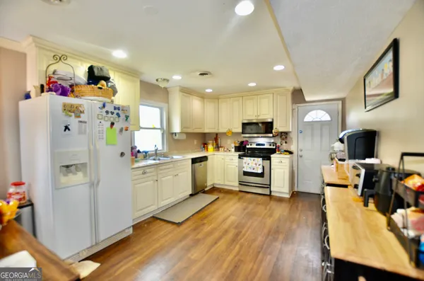 a kitchen with a refrigerator a stove top oven a sink dishwasher and wooden cabinets with wooden floor