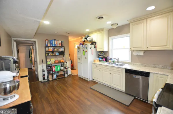 a kitchen with stainless steel appliances a stove a sink a refrigerator white cabinets and wooden floor