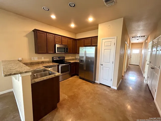 a kitchen with stainless steel appliances granite countertop a refrigerator a stove a sink a washer dryer and a refrigerator