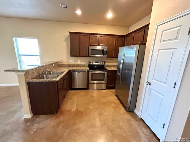 a kitchen with stainless steel appliances granite countertop a refrigerator a stove and a sink