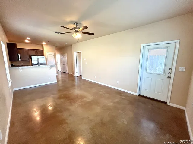 a view of a livingroom with a ceiling fan and kitchen space