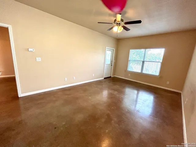 an empty room with windows and ceiling fan