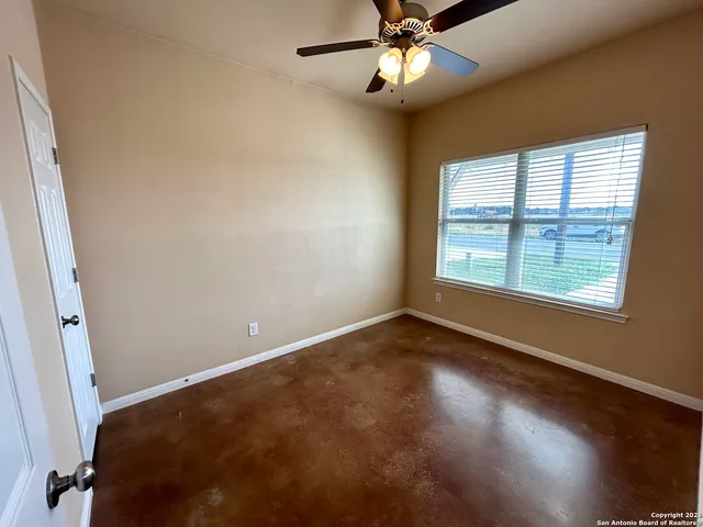 an empty room with wooden floor fan and windows
