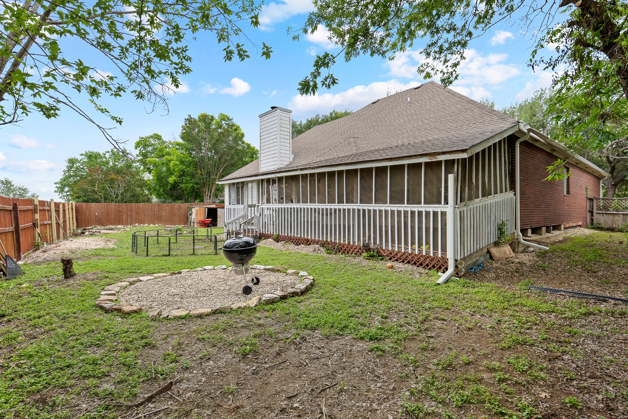 11737 Rydalwater Lane Austin, TX 78754 - Photo 40 of 40 Expansive backyard featuring a screened porch, privacy fencing, brick exterior, and a built-in outdoor gathering area with stone edging