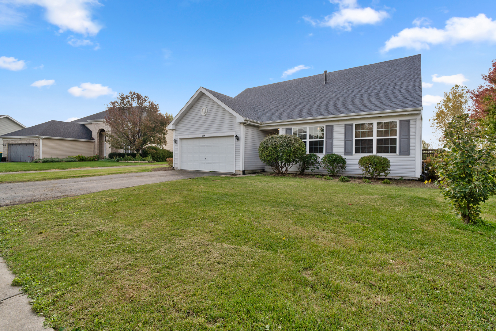 a view of a house next to a big yard and large trees