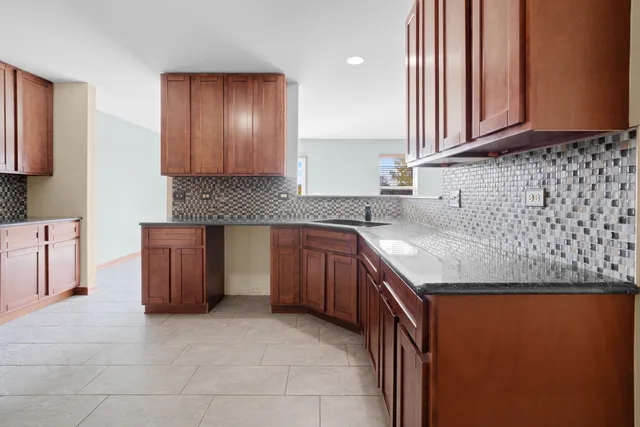 a kitchen with granite countertop a sink a stove a oven and wooden cabinets