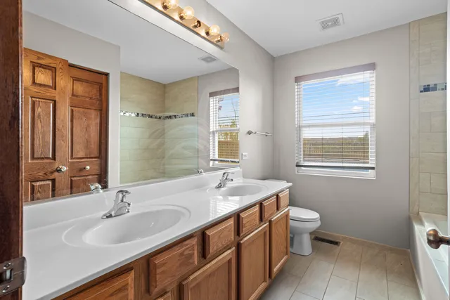 a bathroom with a granite countertop sink a toilet a mirror and a window