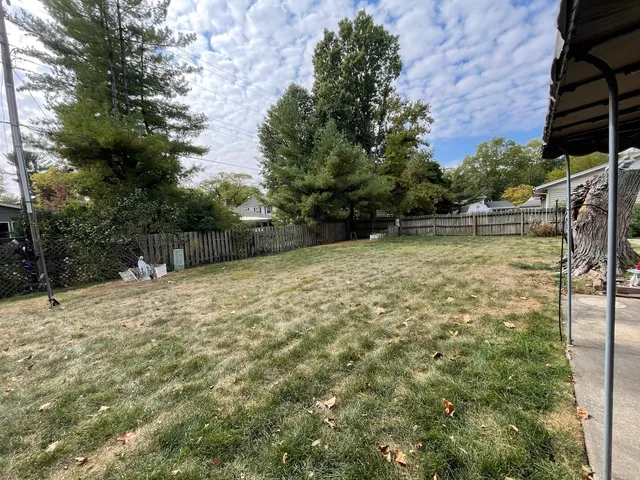 a view of a backyard with a large tree and wooden fence