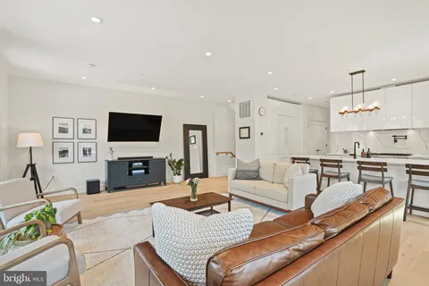 a living room with furniture a flat screen tv and kitchen view