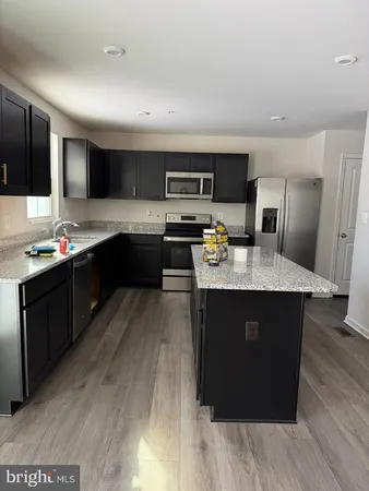 a kitchen with kitchen island granite countertop a sink dishwasher stove and oven with wooden cabinets