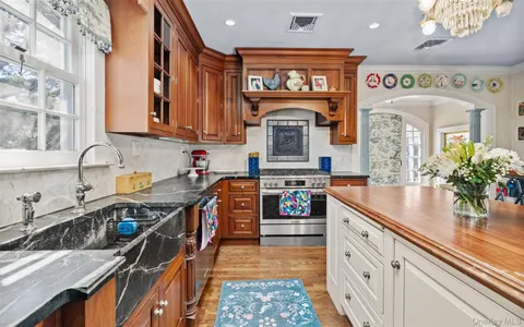 a kitchen with stainless steel appliances granite countertop a stove top oven a sink a dining table and chairs with wooden floor