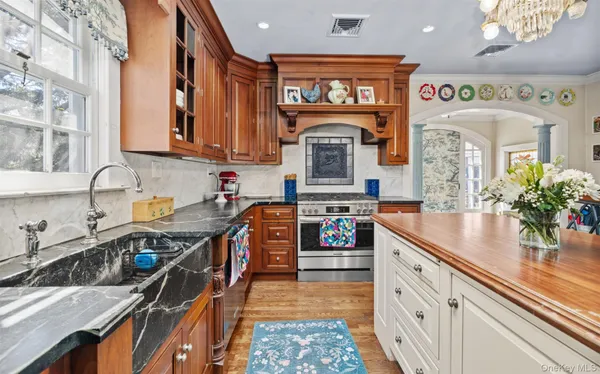 a kitchen with stainless steel appliances granite countertop a stove top oven a sink a dining table and chairs with wooden floor