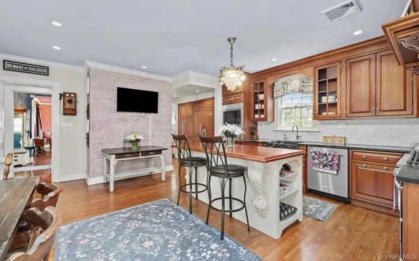 a dining hall with stainless steel appliances granite countertop a stove a sink a dining table and chairs with wooden floor