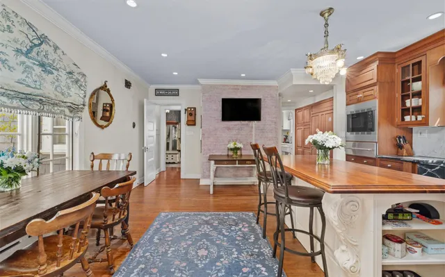 a kitchen with stainless steel appliances kitchen island granite countertop a refrigerator a stove top oven and a dining table with wooden floor